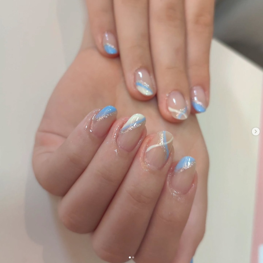 Nail art com linhas azuis e brancas sobre base natural